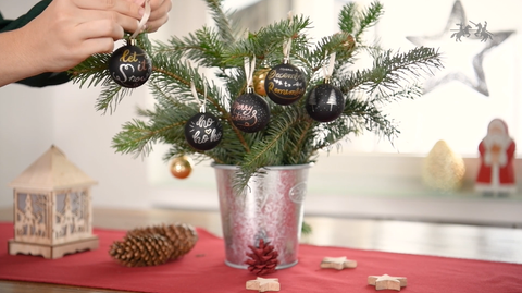 Hand putting ornaments on the Christmas tree