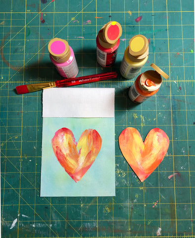 Watercolor fabric square with heart stamp and paints.