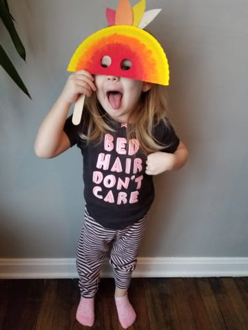 Child holding Mardi Gras paper plate face mask