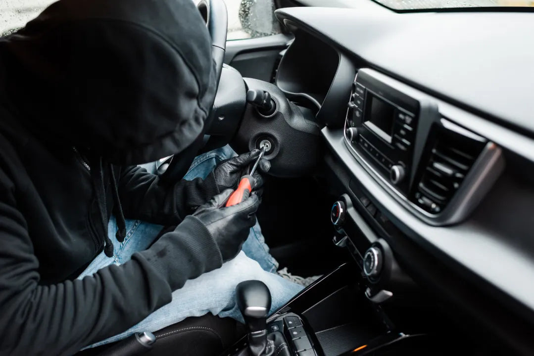 A man in mask stealing a car with screwdriver