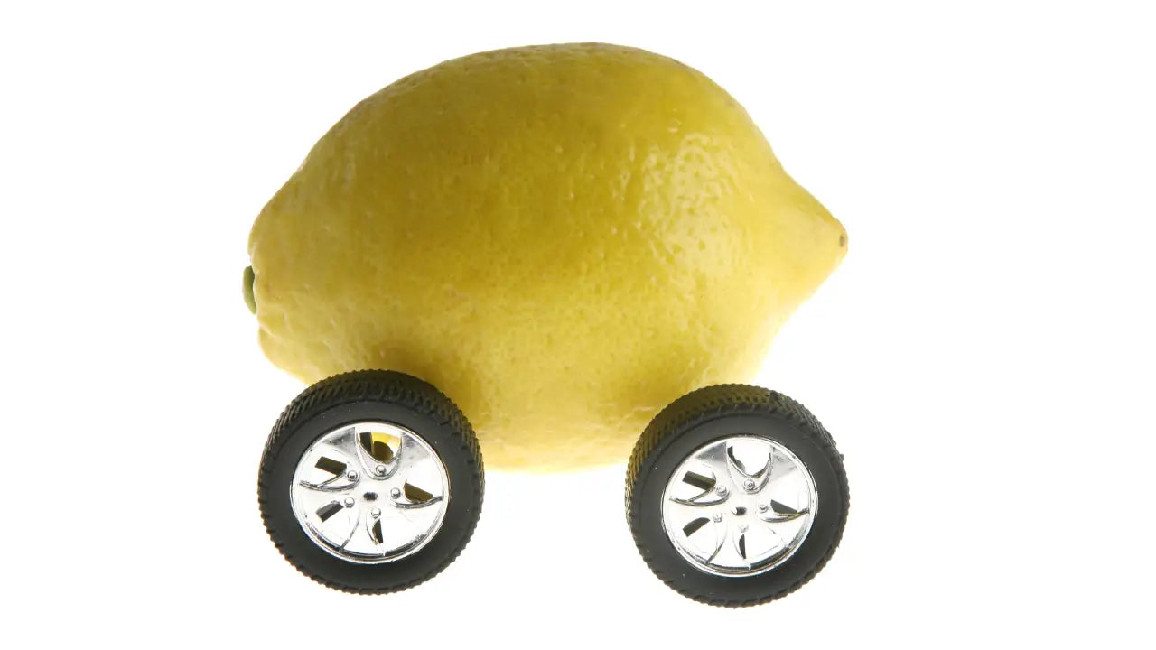 A lemon with toy car tires to symbolize a lemon car.