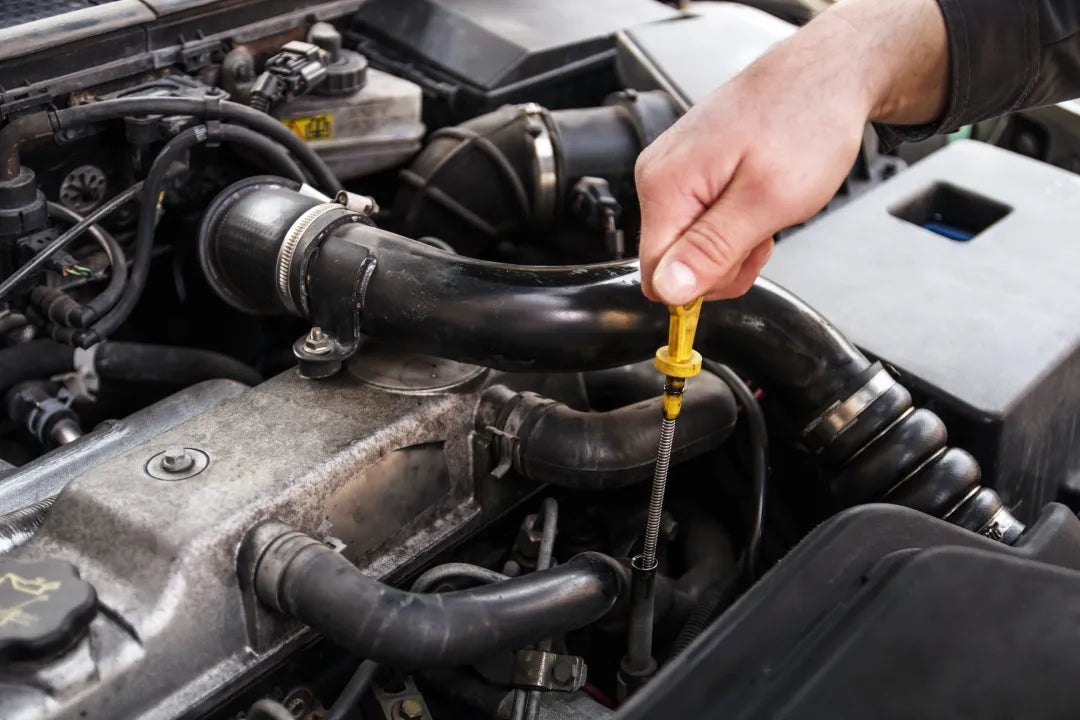 A person checking the oil with the dipstick