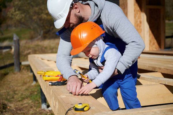 Tradesman holding a child while on a worksite.