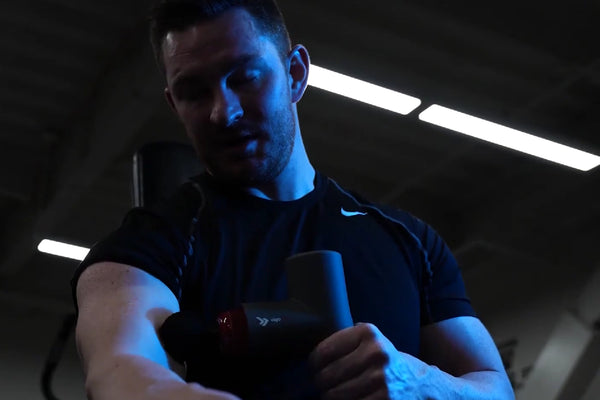 Man using a massage gun to provide pain relief.