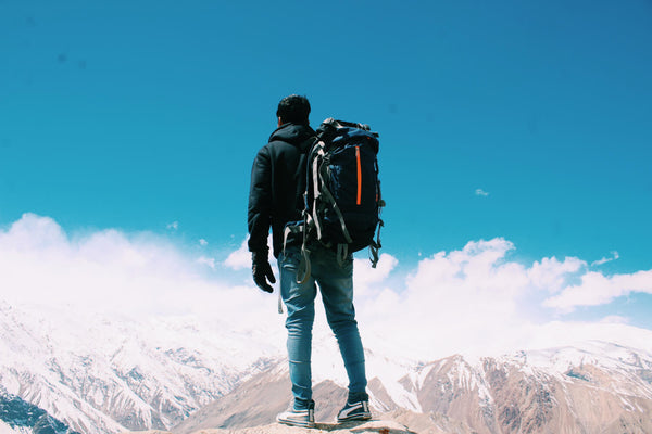 Individual triumphantly standing atop a mountain, symbolizing overcoming challenges.