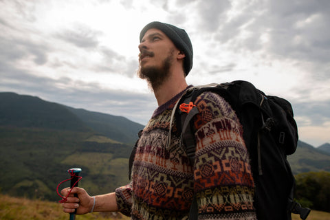 Hiker experiencing the mental health benefits of hiking, standing atop a mountain with a breathtaking panoramic view, embodying tranquility and a sense of accomplishment.