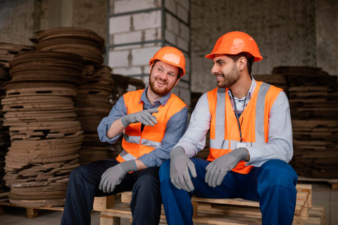 A worker taking a well-deserved break, sitting comfortably with safety gear on, perhaps enjoying a moment of quiet or a laugh with colleagues, highlighting the importance of rest and camaraderie in physically demanding jobs.