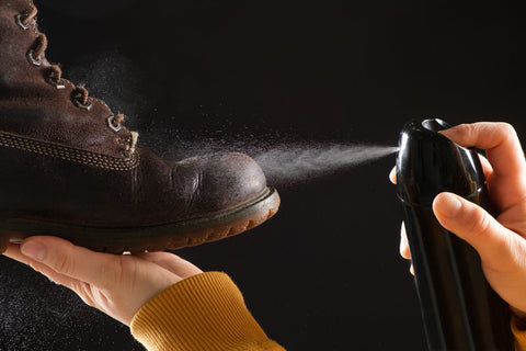 Applying waterproof spray to a shoe