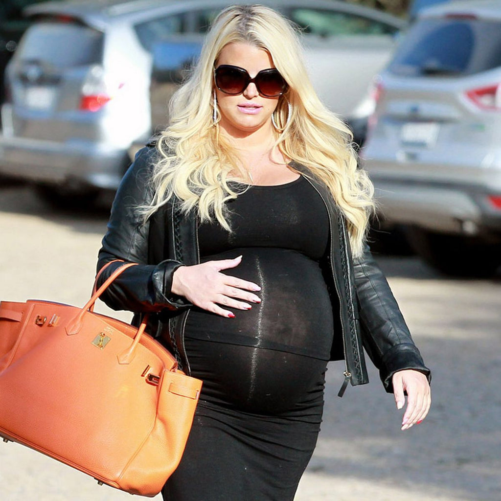 Jessica Simpson pregnant in black dress with large beige bag.