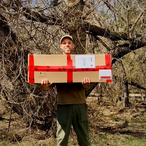 Kurt holding a box filled with trees ready to be shipped out