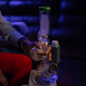 Visual demonstration within 'How to Use a Bong: A Step-by-Step Guide for Smoking Weed' by The DART Company, illustrating the cleaning of a glass bong using a paper towel.
