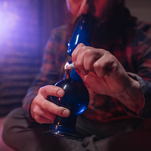 Featured image within 'How to Use a Bong: A Step-by-Step Guide for Smoking Weed' on The DART Company's post, showing a person lighting a bowl with a lighter or hemp wick as part of the bong usage tutorial.