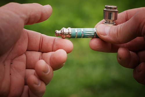 Image featured in 'The Ultimate Guide to Pipe vs Bong for Smoking Weed' on The Dart Company's blog, depicting a person smoking from a metal pipe to underscore the use of metal material in the 'Pipe vs Bong' comparison.