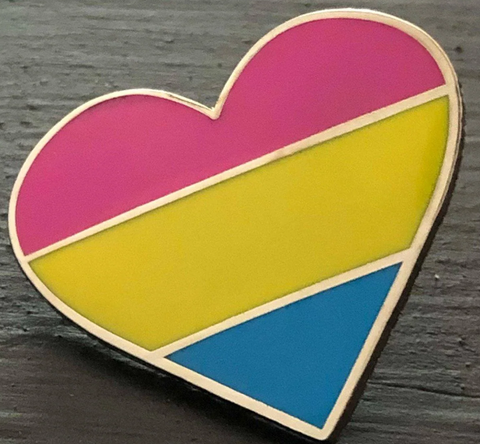 Pansexual Flag Heart Enamel Pin on a dark wooden table