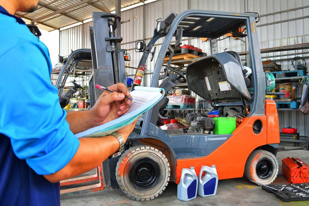 forklift mechanic repairing orange lift in warehouse shop