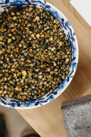 Overhead shot of a blue and white porcelain bowl, filled with multicolored jewels of corn.