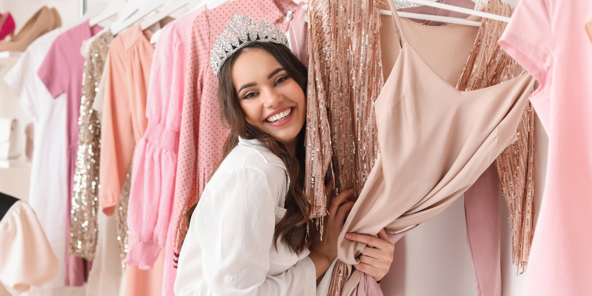 Beautiful happy young girl choosing clothes for high school prom in shop