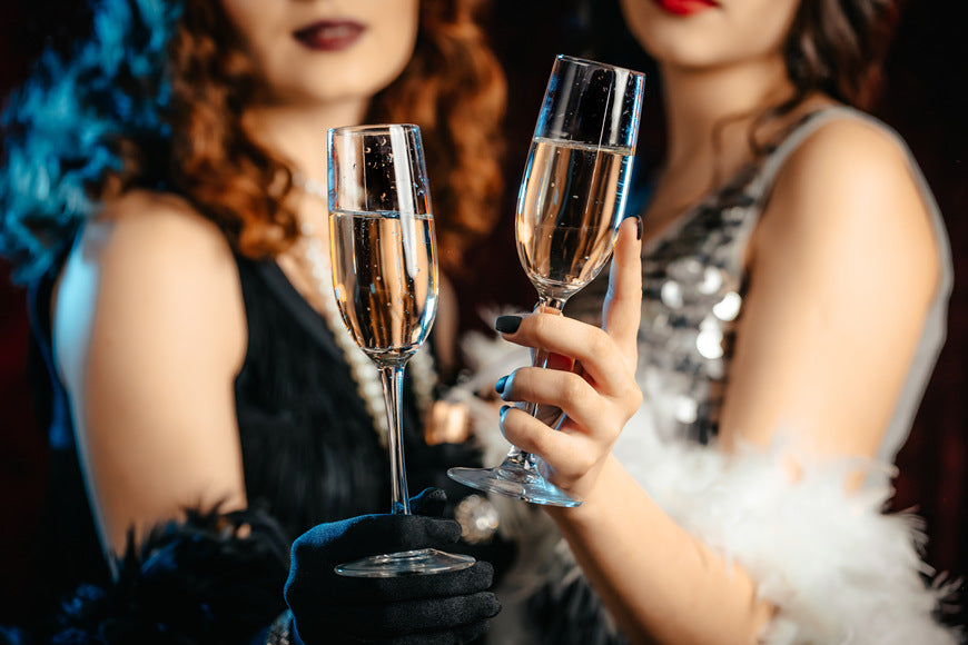 Close-up-glasses-of-champagne_-Flappers-women-wearing-in-style-of-Roaring-Gatsby-twenties-drinking-alcohol_-Vintage-retro-party-fashion-girls-friends-concept