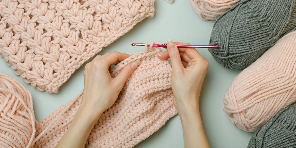 Crochet with your own hands.Knitting threads in pink and gray. Knitted scarf.Female hands hold a crochet hook and knit.DIY.Knitting rules. Creativity lessons.Winter activities during quarantine.