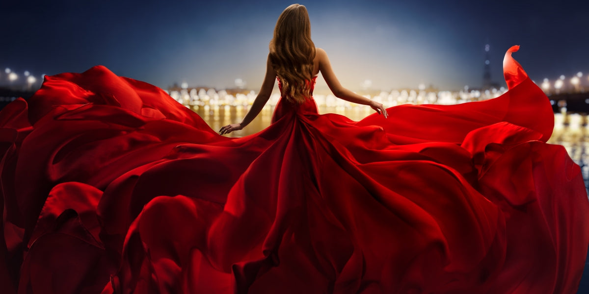 Fashion Woman in Red fluttering Dress Back Side Rear View. Glamour Model dancing with Long Silk Fabric flying on Wind over Night Sky City Light Landscape