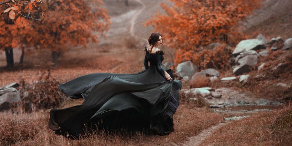 Incredibly stunning girl in a black dress. The background is fantastic autumn. Art photography.