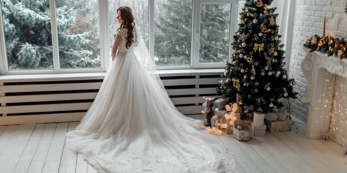 Luxury bride in wedding dress for Christmas near the large panoramic window. Luxury bride in wedding dress for Christmas. Charming bride in an elegant wedding dress. Bride in luxurious suites.