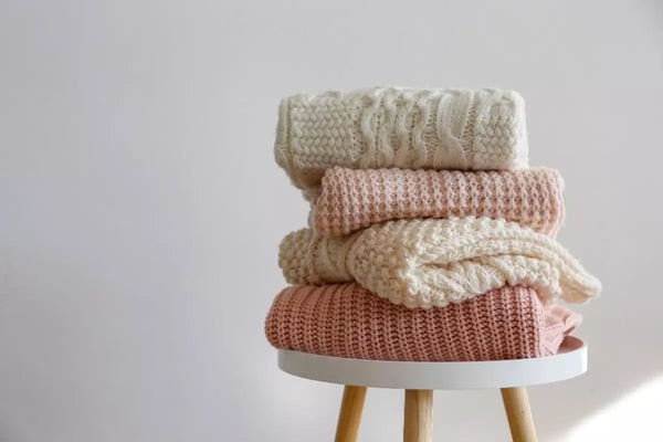 Sweaters are stacked on a table