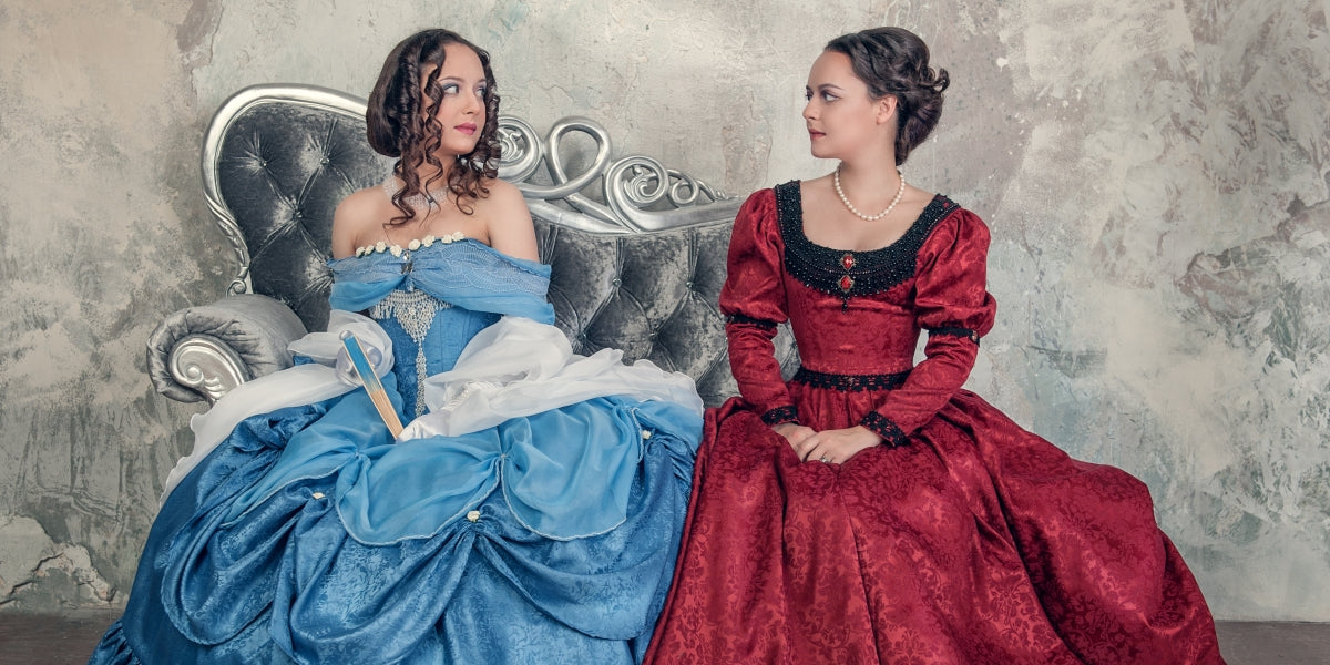 Two beautiful women in medieval dresses on the sofa
