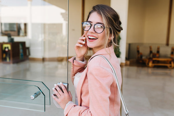 Woman opens the office door while smiling and talking on the phone