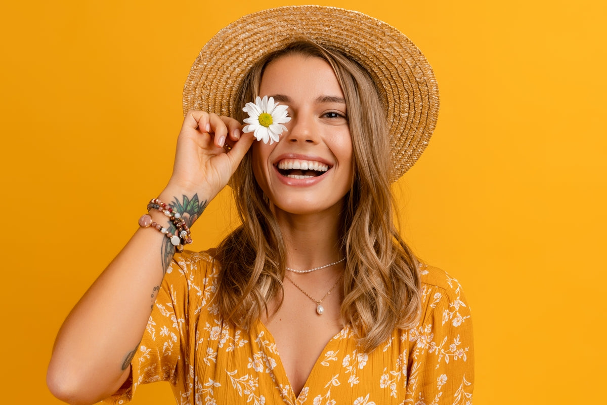 Woman smile while holding a flower over one eye