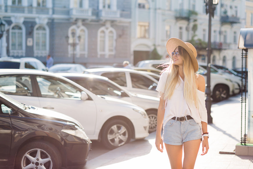 Urban style happy woman is walking on sun with white shirt and blue jeans