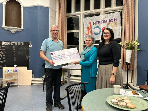 Simon Hirst of River Holme Connections receives a cheque from Greta Bradley of the BGCT and Emma Woods-Bolger of One Community