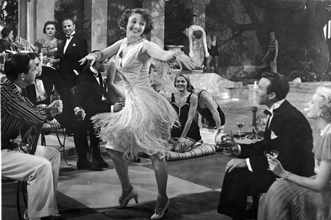 an old black and white image of a women dancing in front of audience