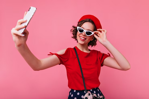 a fashionable lady taking selfie in pink background