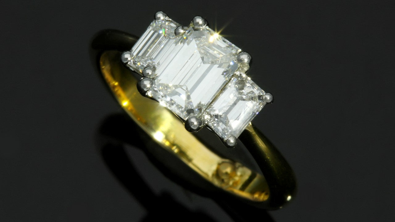 Three stone emerald cut diamond engagement ring yellow gold