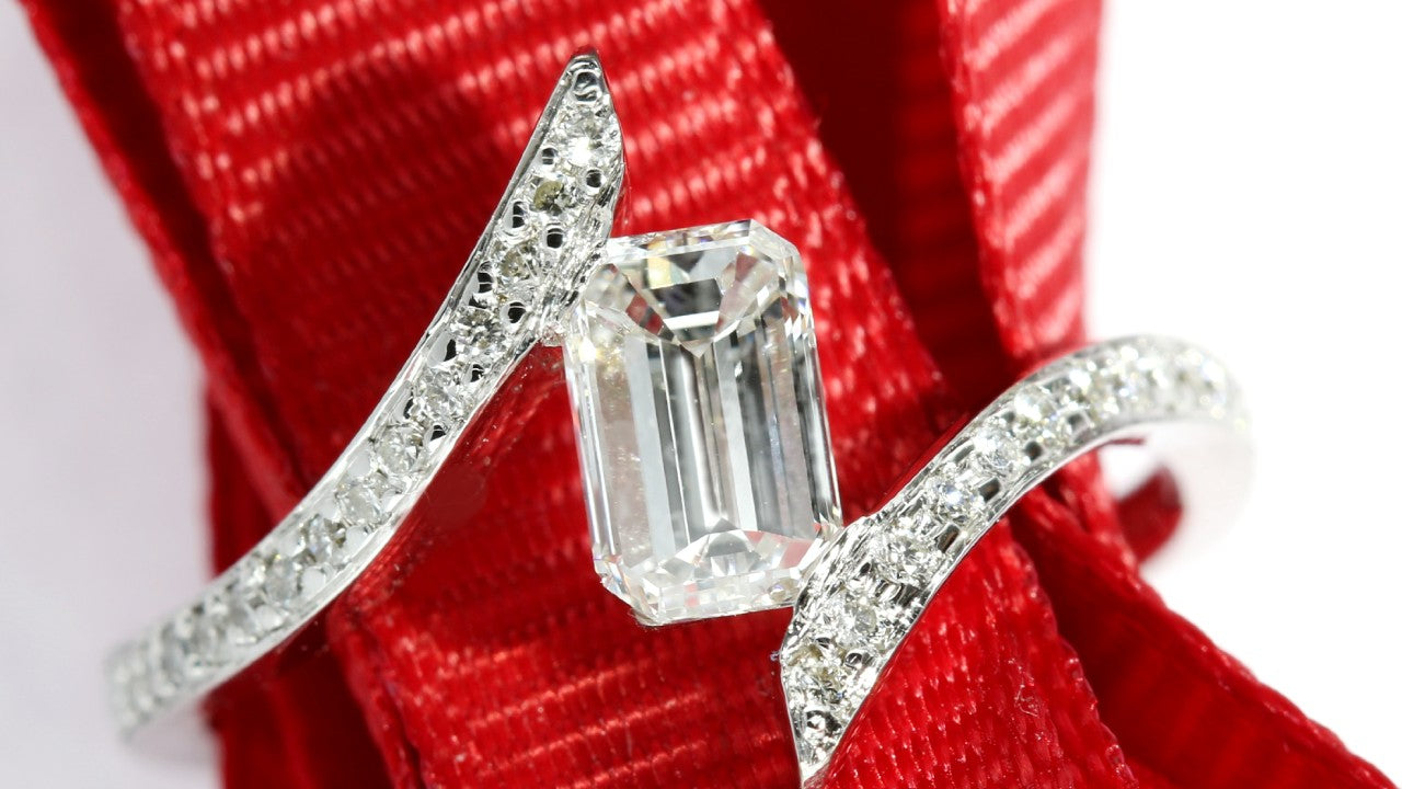 Tension set pave engagement ring set with an emerald cut center diamond