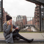 Load image into Gallery viewer, Frau sitzt telefonierend auf Brücke in Speicherstadt und trägt bordeaux Handyband
