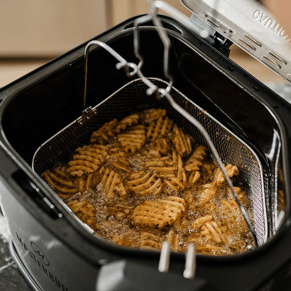 Waffle cut fried simmer in hot oil. The bailing wire of the fryer basket is up and attached to a 2-prong hook, making the basket easy to remove.