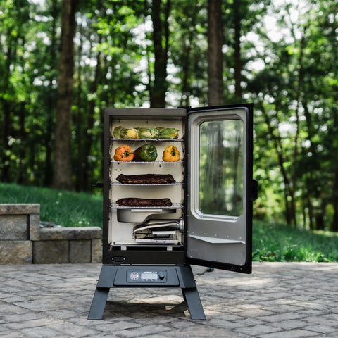 An open 710 WiFi smoker sitting outside on a brick patio. The smoker is open to display 4 racks of food and the removable water bowl.