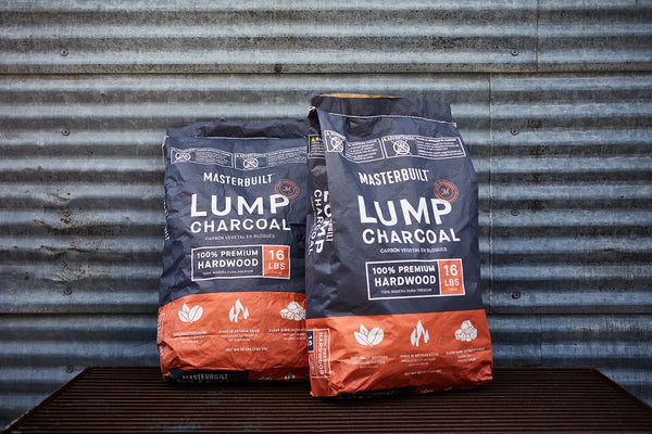 Two bags of Masterbuilt Lump Charcoal lean against a corrugated metal wall