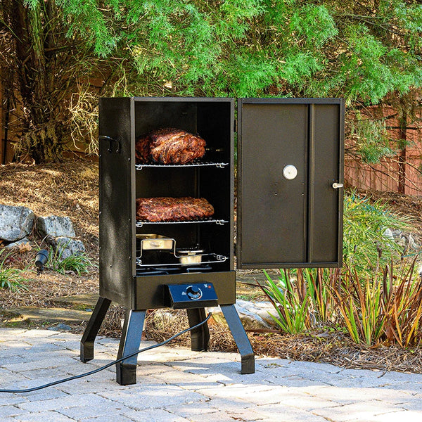 An Analog Electric Smoker sits on a patio with its door open to show 2 racks of food above the wood chip and water pans