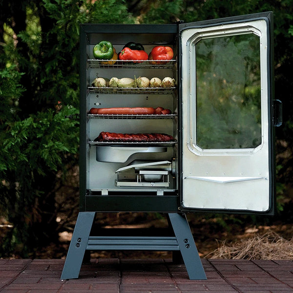 A digital electric smoker sits on a brick patio with it's door open to show4 racks of food and the water and wood chip trays.