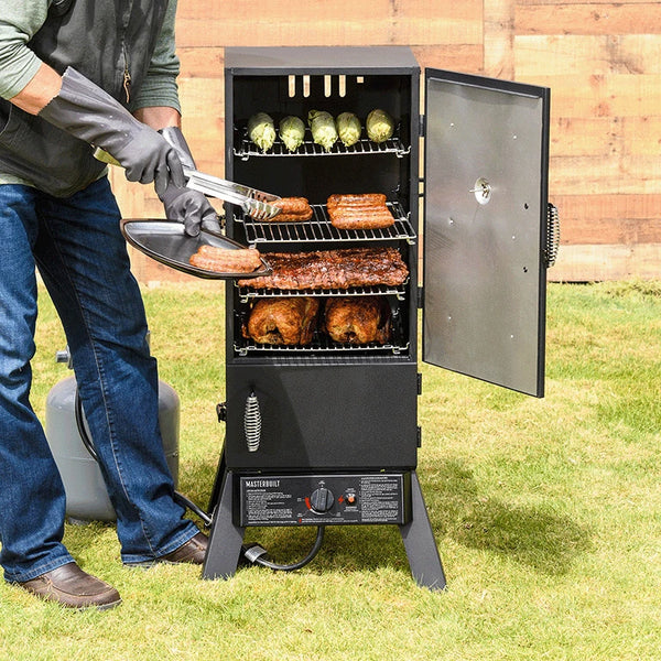 A man removed cooked sausages from a Masterbuilt propane smoker. Corn on the cob, racks of ribs, and 2 whole chickens rest on other racks of the smoker ready for serving