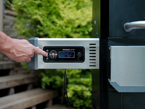 The digital control panel of a Gravity Series Grill + Smoker. The panel extends from the left of the grill. A person's hand is visible as the person adjusts the grill settings.