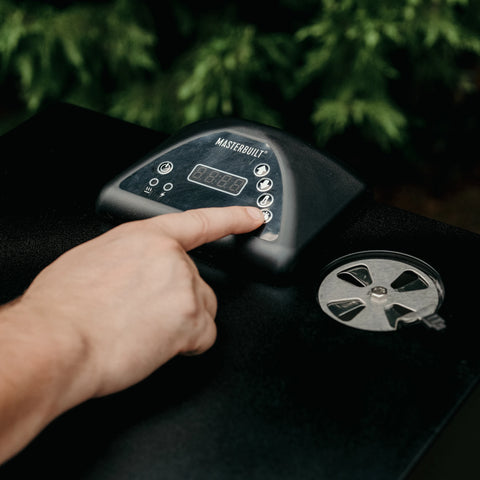 The control panel on top of a Masterbuilt vertical smoker with an open air damper to the right. A person's hand is visible as the person adjusts the smoker settings.