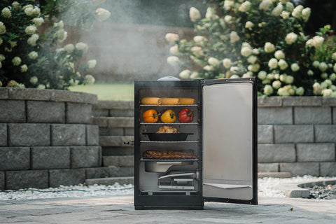 An open vertical smoker with 4 racks of food sits on a paved patio