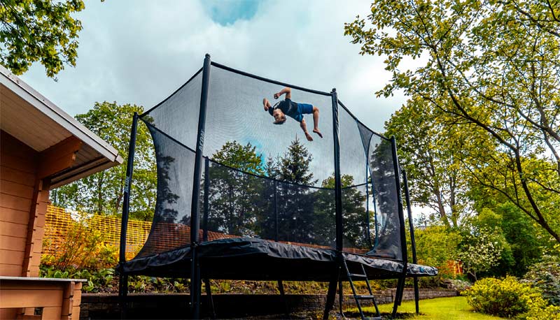 Backflip on the Acon HD Trampoline with safety net in the summer backyard