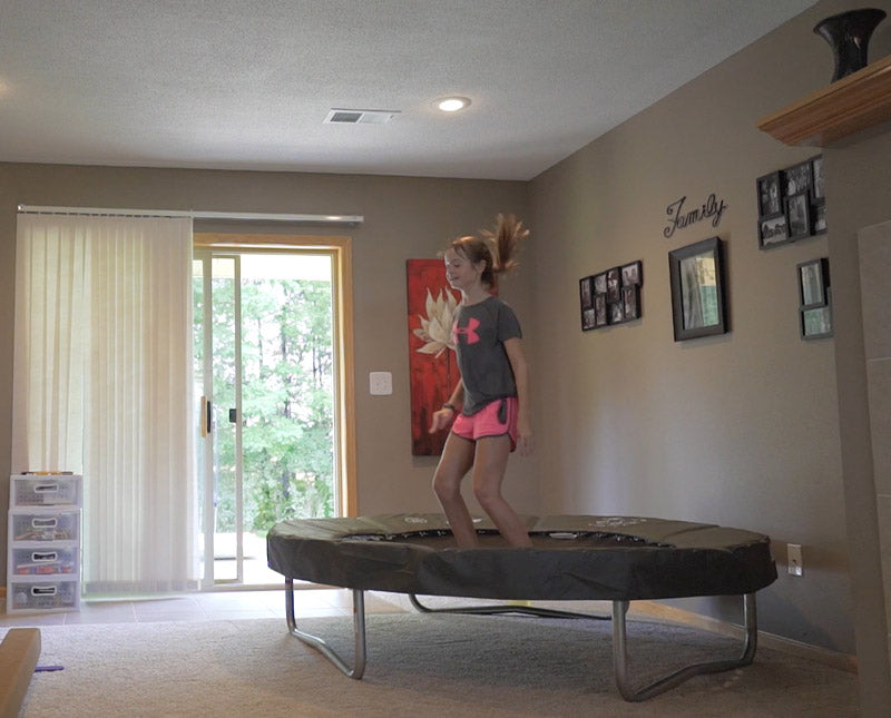 A girl jumping on a Baby Acon trampoline indoors