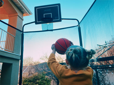 A child aims a basketball at the Acon Trampoline Basketball Hoop