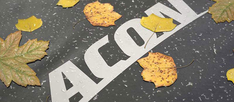 Fall leaves on a trampoline weather cover. Image is a close-up and the brand logo is visible in white.